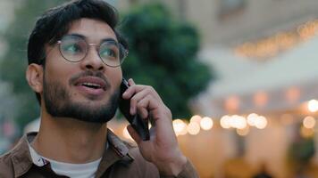 Lycklig leende indisk arab etnisk manlig man turist resande affärsman studerande kille har vänlig prata konversation tala gående svar mobil telefon ring upp sightseeing reser stad gata video