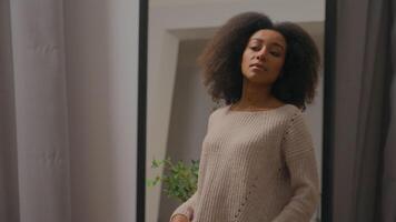 elegant etnisch Afrikaanse Amerikaans vrouw op zoek Bij spiegel reflectie meisje vervelend jumper mode gewoontjes kleding bewonderen verwennerij voorbereidingen treffen voor datum vrouw klant boodschappen doen in kleding winkel dressing kamer video