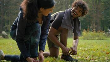 dois desportivo pessoas fixação tênis gravata cadarço do sapatos juntos falando conversação casal árabe homem desportista e indiano mulher desportista preparar para corre ginástica esporte exercite-se caminhando dentro parque video