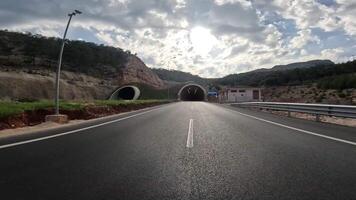 Highway journey into tunnel captured from car view. shows car approach, enter highway tunnel, highlighting highway, tunnel interaction. Visuals focus on highway, tunnel entrance and inside video