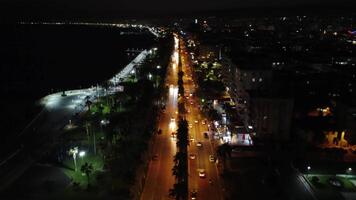 zangão Visão do mersin às noite, exibindo aterro, rua com carros. iluminado Mersin, noite cena com ocupado rua capturado. noite dentro Mersin, zangão cenas do rua e aterro video