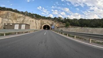 Car drives through tunnel, capturing tunnel, car point of view. shows darkness then emergence, highlighting tunnel, car point of view. Focuses on journey, tunnel, car point of view from inside video