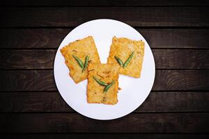 Three tempe, fried flour with chilies served on a white plate. photo