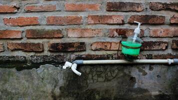 a faucet and a bottle of soap against a backdrop of red brick walls. photo