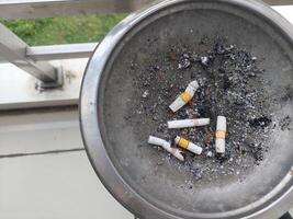 Cigarette butts and ashes on ashtray top view photo