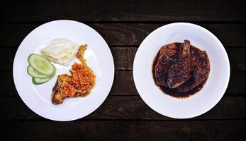 Side dish, sweet spicy chicken dish is on white plate on dark wooden background, top view. photo