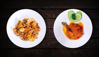 Side dish, sweet spicy chicken dish is on white plate on dark wooden background, top view. photo