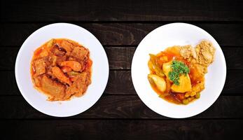 Side dishes, sweet and sour fish dish, Javanese spicy stew on white plate on dark wooden background, top view. photo