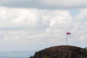 el rojo y blanco indonesio bandera moscas terminado el pico de un antiguo volcán, jogjakarta. foto