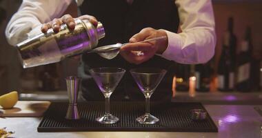 professionnel barman dans une blanc chemise et noir tablier fabrication cocktail. coup sur rouge caméra 4k dans lent mouvement video