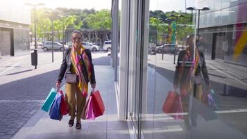 Happy senior attractive lady with shopping bags walking in the street smiling. Entering in a mall. video