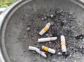 Cigarette butts and ashes on ashtray top view photo