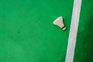 Top view. White badminton shuttlecock with a white stripe on the green floor on the right. photo