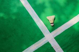 Top view, White badminton shuttlecock on green floor with crossed white stripes. photo