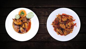 Side dishes, bean vegetable dish and chicken spicy are on white plate on dark wooden background, top view. photo