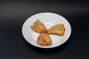 Three fried bananas are served on a white plate. photo