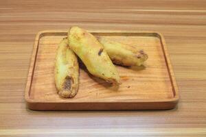 Three fried bananas on a wooden tray at the top view photo