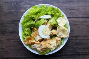 A green vegan salad made from a mixture of green leaves and vegetables sprinkled with crackers and half a boiled egg. photo
