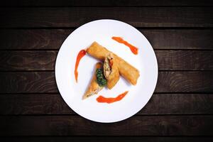 spring rolls with sweet chili sauce filled with chicken and vegetables served on a white plate. photo