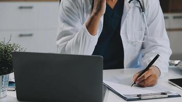 dokter werken met laptop computer en schrijven Aan papierwerk. ziekenhuis achtergrond. video