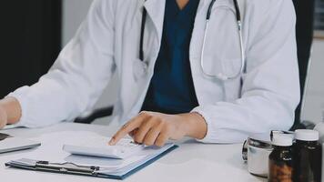 Doctor working with laptop computer and writing on paperwork. Hospital background. video