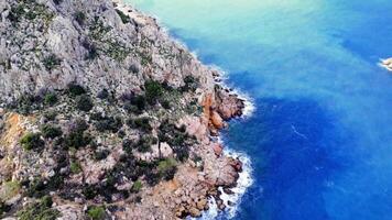 Birds eye view captures foamy waves, rocky shore, highlighting sea, coast. emphasizes dynamic interaction of sea, coast. Footage reveals natural beauty of sea, coast video