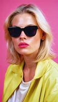 photo of beautiful woman with blonde hair and style sunglasses standing against pink background,