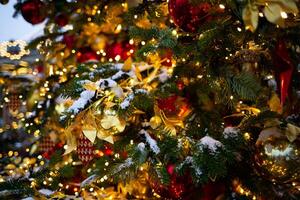 beautiful multi-colored toys on a Christmas tree against the background of lights and snow photo