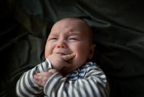 mixed race newborn crying baby lies wrapped in a green muslin swaddle photo