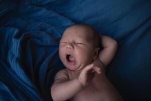 mixed race newborn baby lies wrapped in a blue muslin swaddle photo