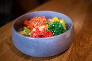 Poke bowl with salmon, rice, avocado, edamame beans, cucumber and radish in a gray bowl. Hawaiian ahi poke bowl, gray background photo