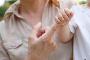 close-up shot the baby is holding on to his mother's finger photo