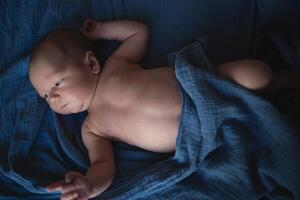 mixed race newborn baby lies wrapped in a blue muslin swaddle photo