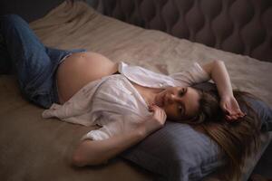 joven hermosa embarazada mujer mentiras en el cama en el dormitorio foto