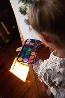 little cute girl draws with paints on canvas at the easel photo