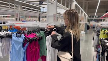 une Jeune femme choisit une chemise dans une Vêtements boutique video