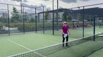 porträtt av positiv ung kvinna med racket och padel boll på tennis domstol video