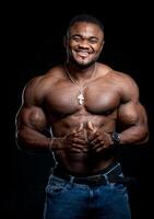 Professional african american sportsman posing on camera with no shirt. Black studio background. Smiling athlete. Closeup. photo