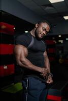 Sporty athletic man training his biceps in gym. Young bodybuilder posing in gym for camera. photo