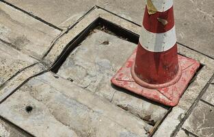 manhole cover is damaged and collapsed. Use traffic cones to warn road users to be careful. closeup photo