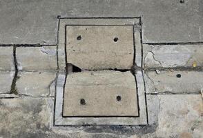 cement tile covering the manhole cover is damaged and has a hole. photo