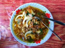 soto es un típico indonesio sopa plato consistente de carne caldo con varios empastes de huevo, pollo o vaca carne, vaso fideos, repollo, algún tiempo con frijol coles. foto