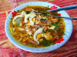 soto es un típico indonesio sopa plato consistente de carne caldo con varios empastes de huevo, pollo o vaca carne, vaso fideos, repollo, algún tiempo con frijol coles. foto