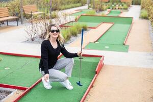 Playing Adventure Golf, downhill shot, ball, club and hole. photo