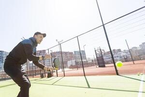 Man playing padel in a green grass padel court indoor behind the net photo