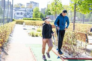 The girl is preparing to hit the ball with a golf club and looks at the man who is squatting next to her with the golf club in his hands. photo