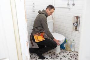 Plumber repairing a toilet cistern photo