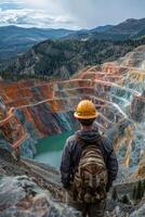 Surveying the copper mine, man in hard hat oversees operations at open pit - ensuring safety and efficiency in resource extraction. photo