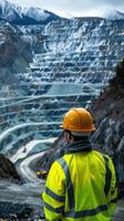 Surveying the copper mine, man in hard hat oversees operations at open pit - ensuring safety and efficiency in resource extraction. photo