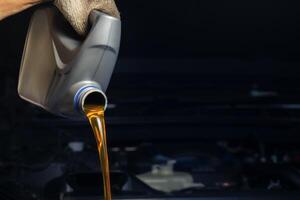 Pour engine oil from the lubricant bottle. Engine background, oil change shop engine service industry photo